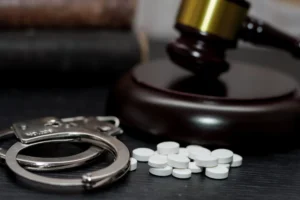 Handcuffs and drug pills sit in front of a justice gavel. Get an experienced drug crimes lawyer in Texas to defend you against serious charges. Call us.