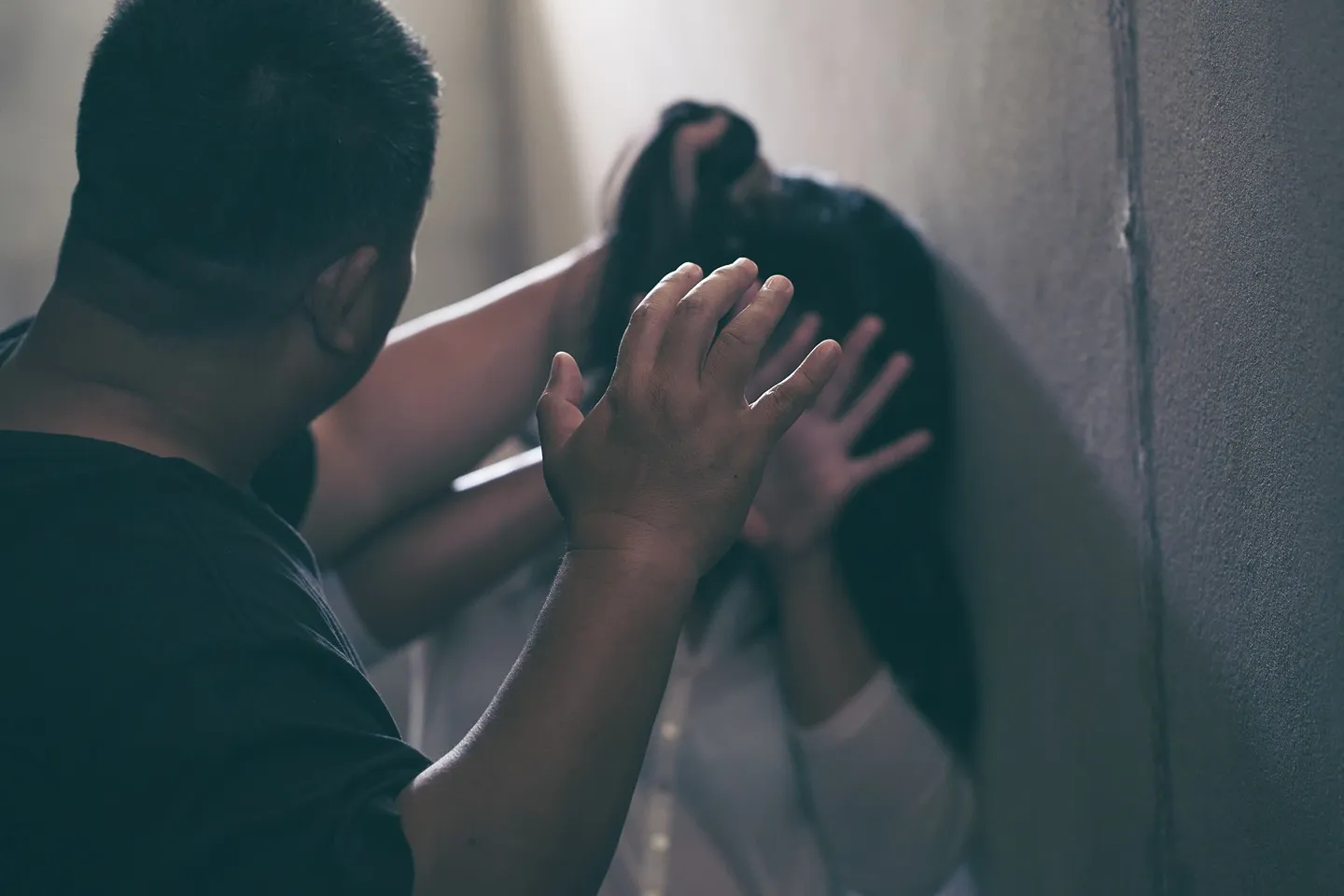 An angry man holding a woman's hair with his hand raised.