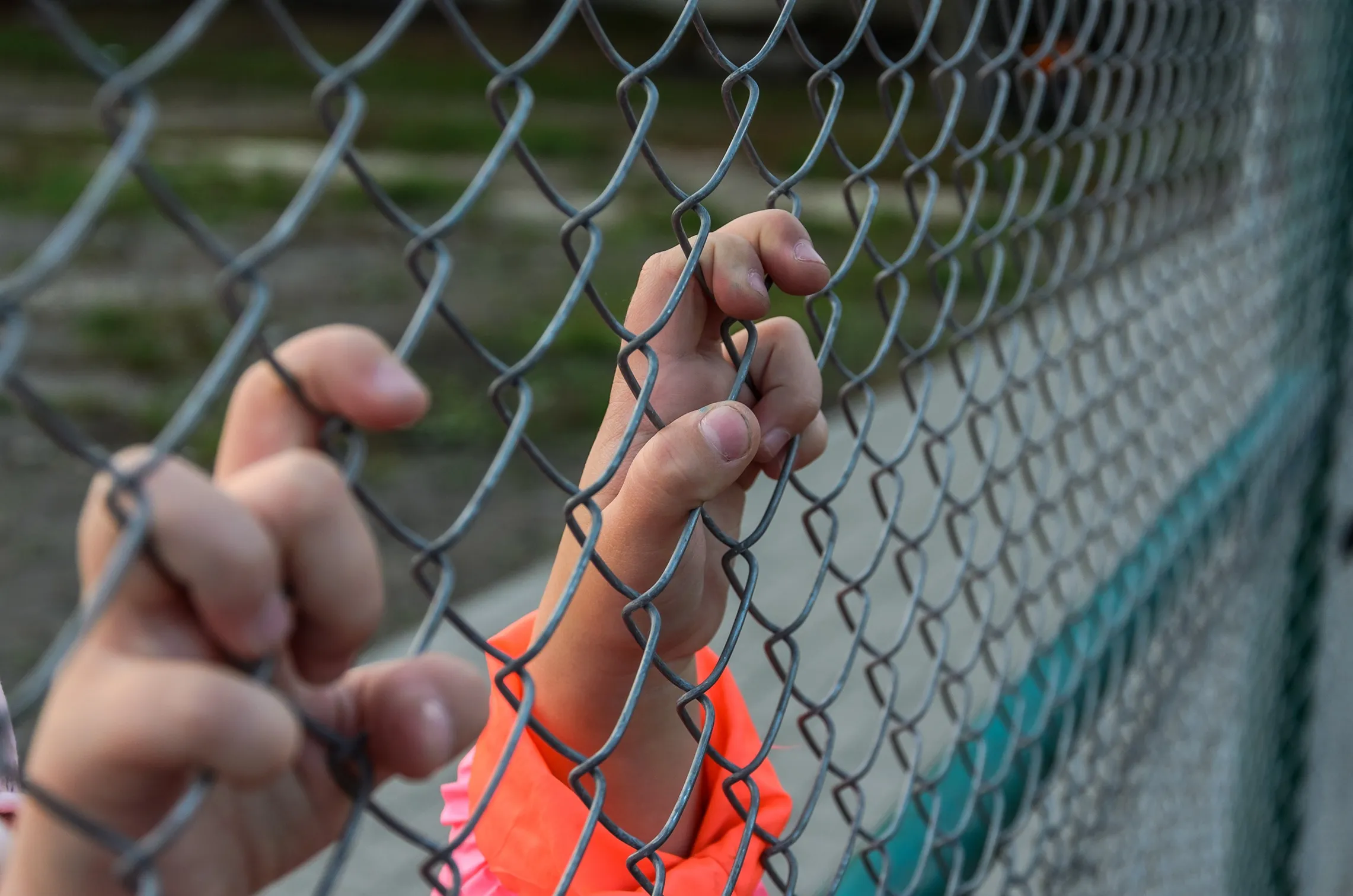Someone in a jump suit holding a fence.