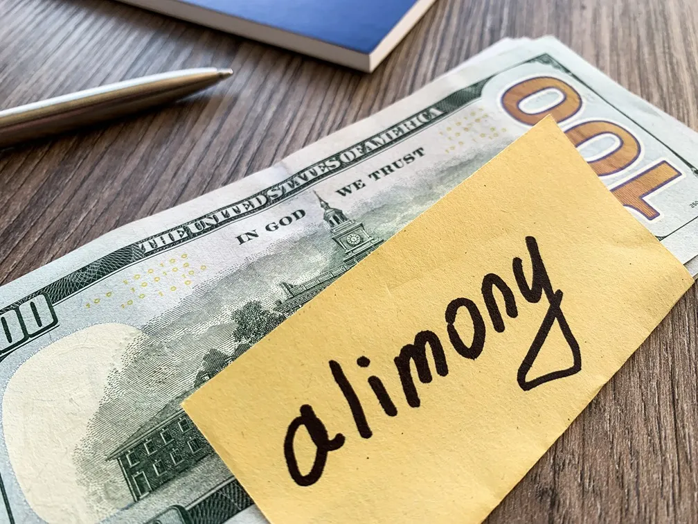 Alimony written on a scrap of paper on top of money. 