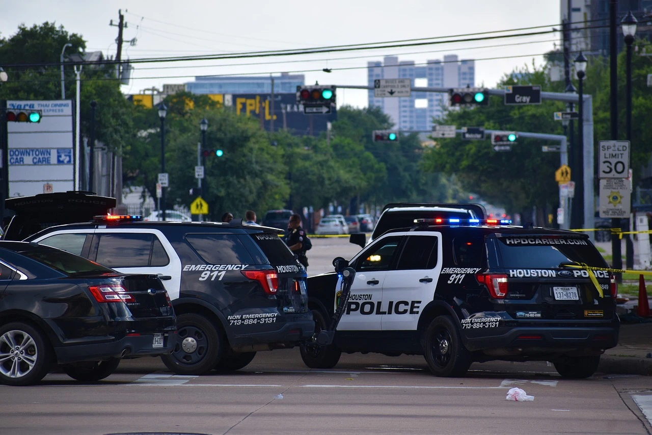 Houston police SUVs at an intersection on the road. The police are making a criminal arrest.