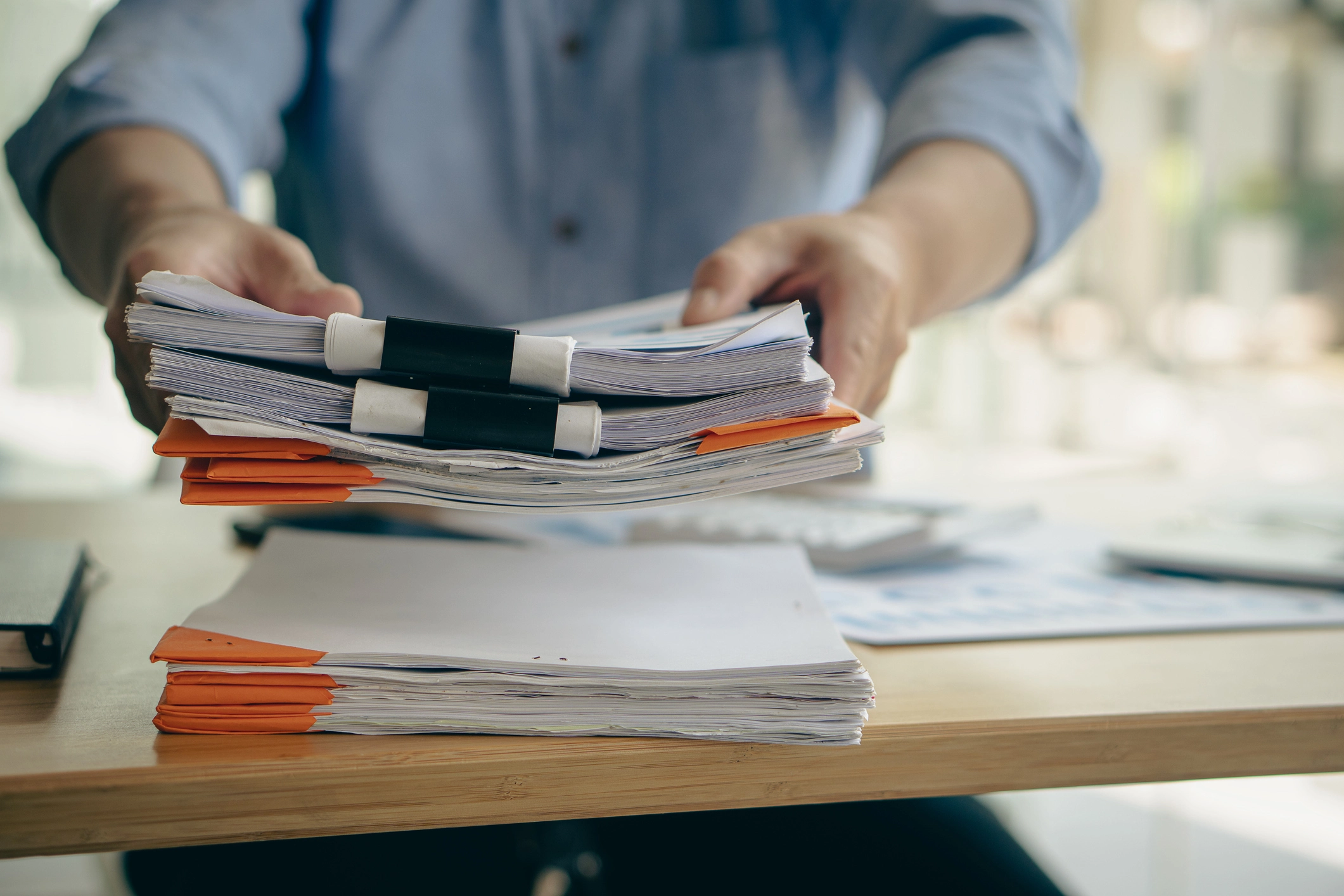 A man handling documents in large binder clips.