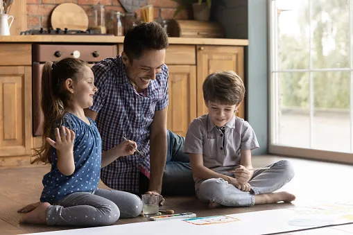 Parent with two children on the floor playing.
