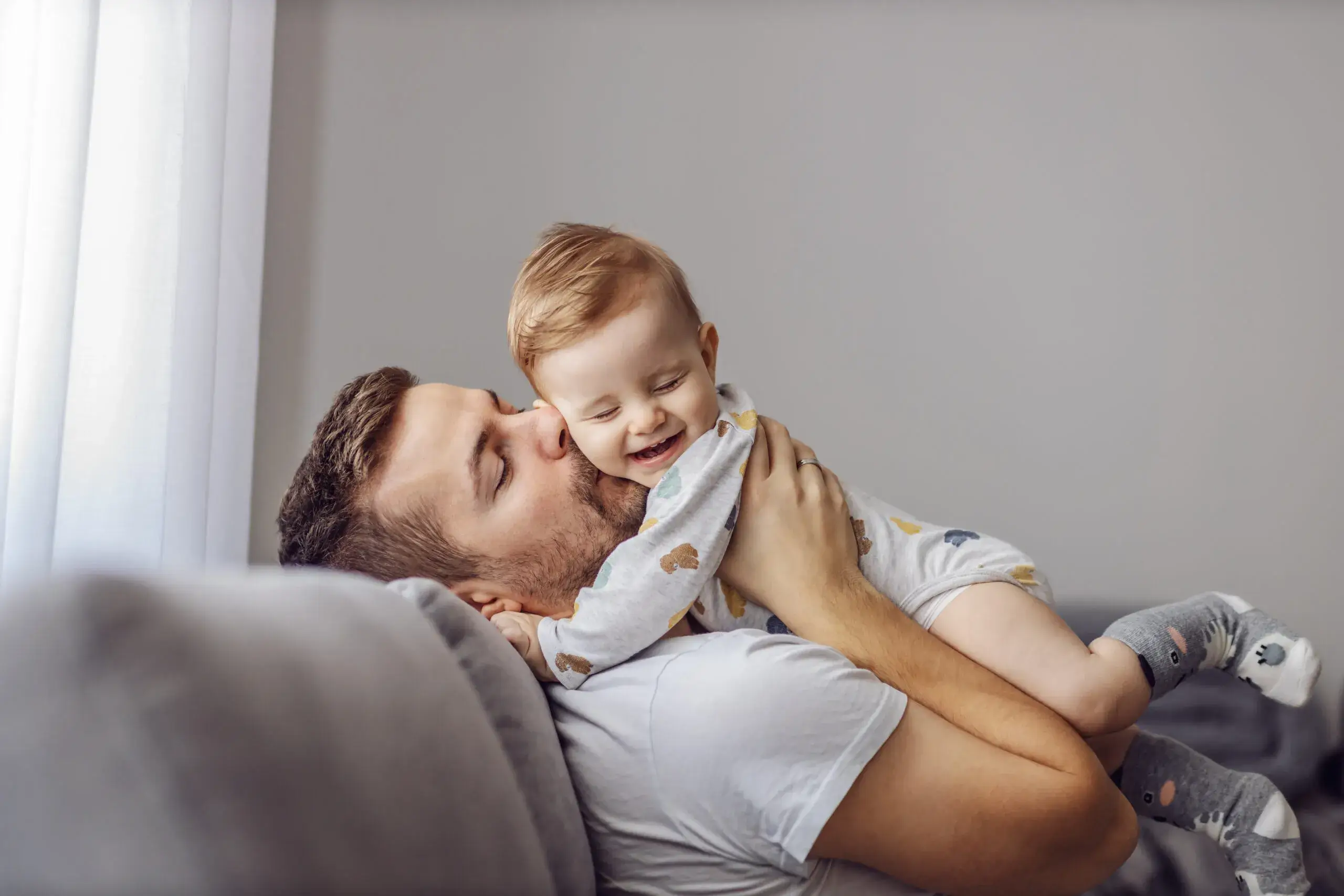 Father kisses happy baby. Call us for a family lawyer in Sugar Land, TX who understands the complexities of establishing or making changes to paternity rights.