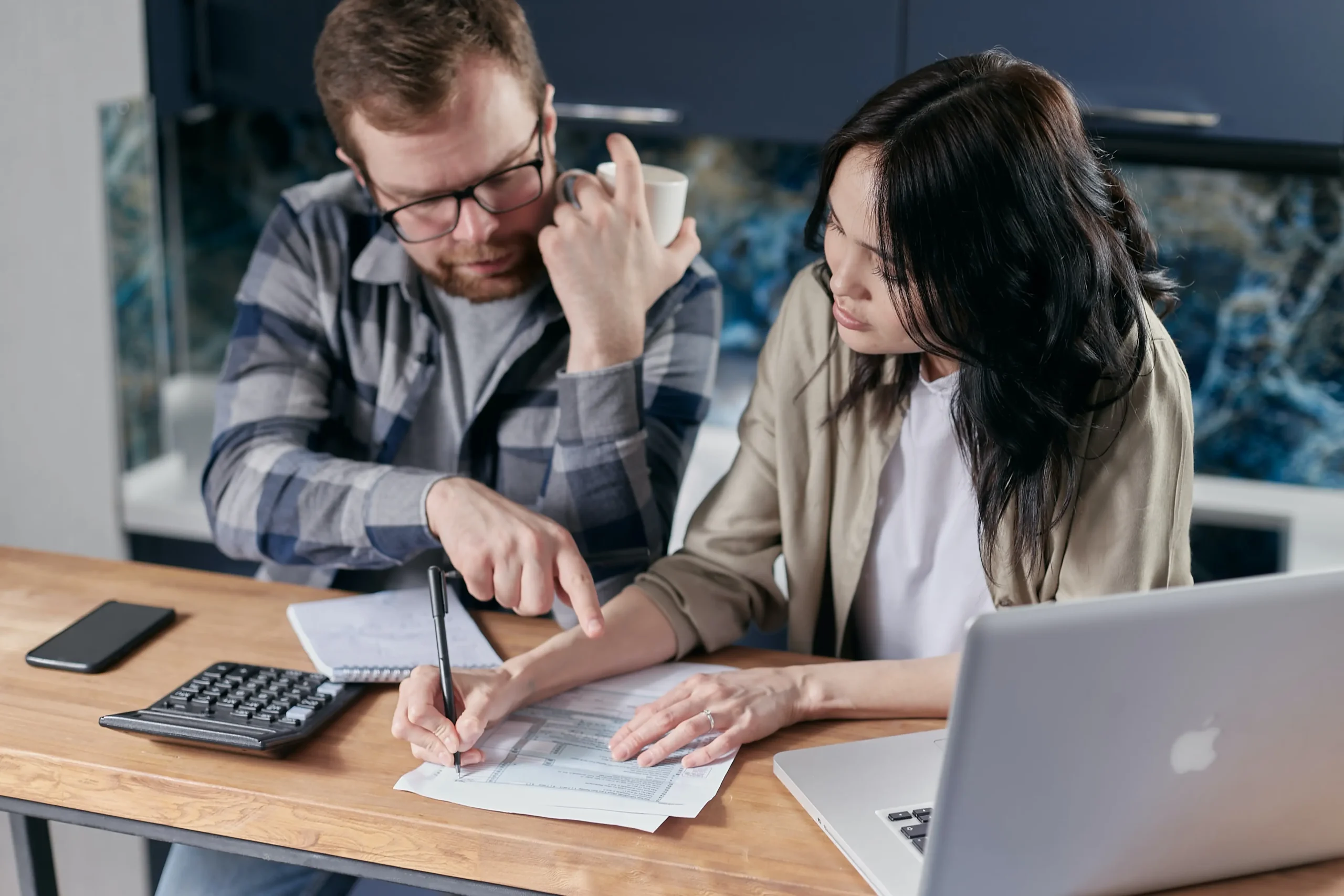 Couple looking over paperwork with a calculator.