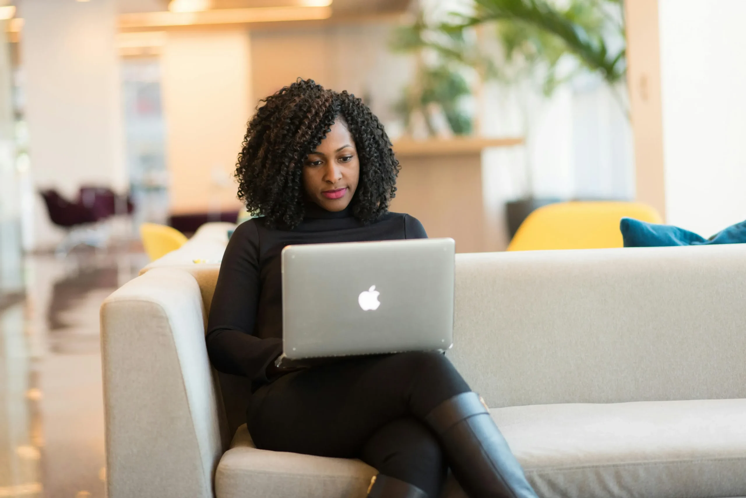 Women sitting on a couch using a laptop.