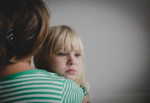 A child looking over her parent's shoulder.