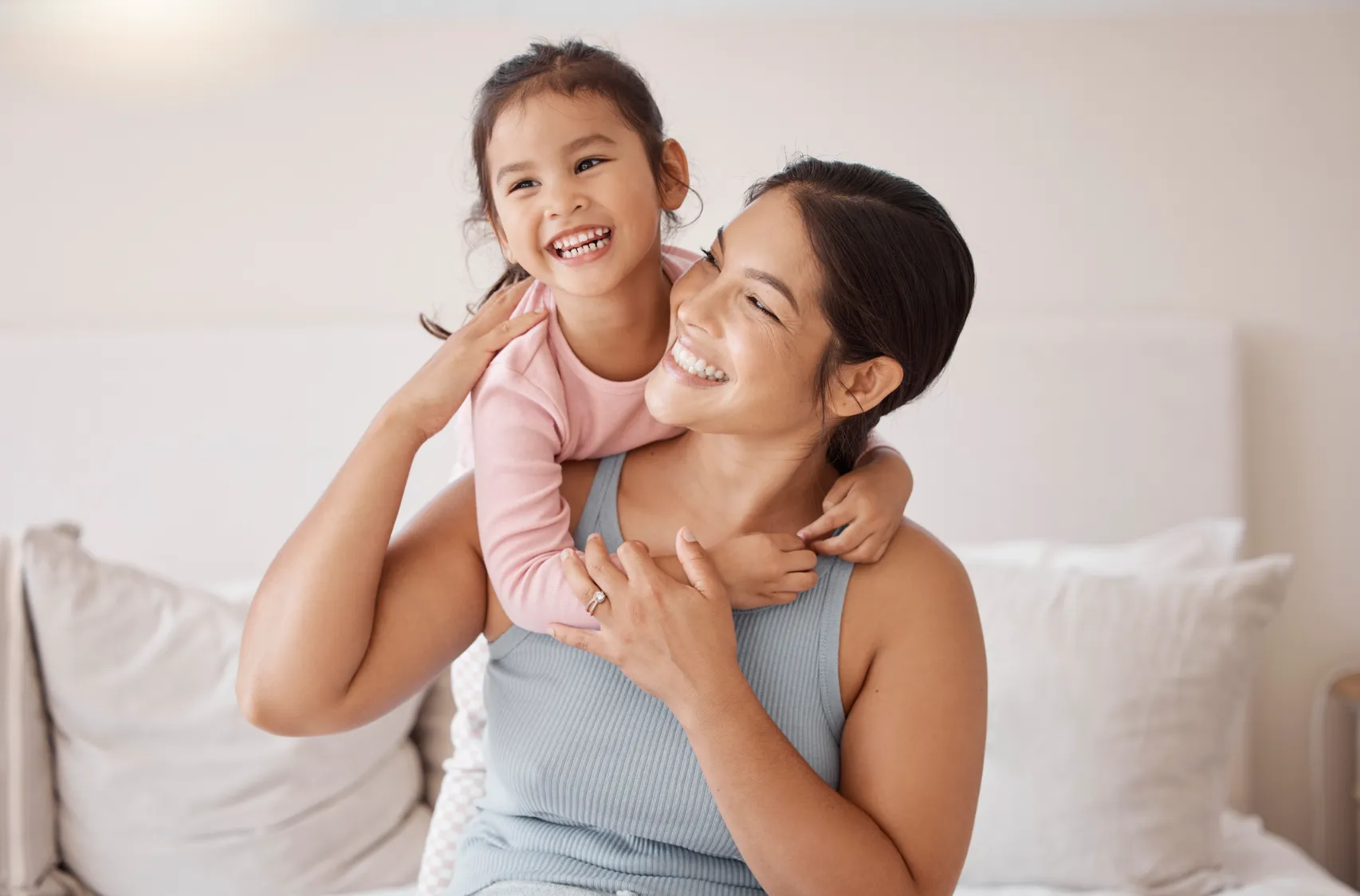 A daughter hugging her mother from behind.