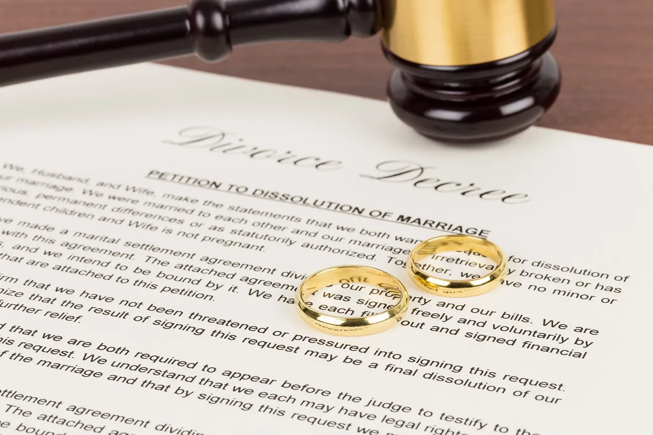 A divorce decree with a gavel and two wedding rings.