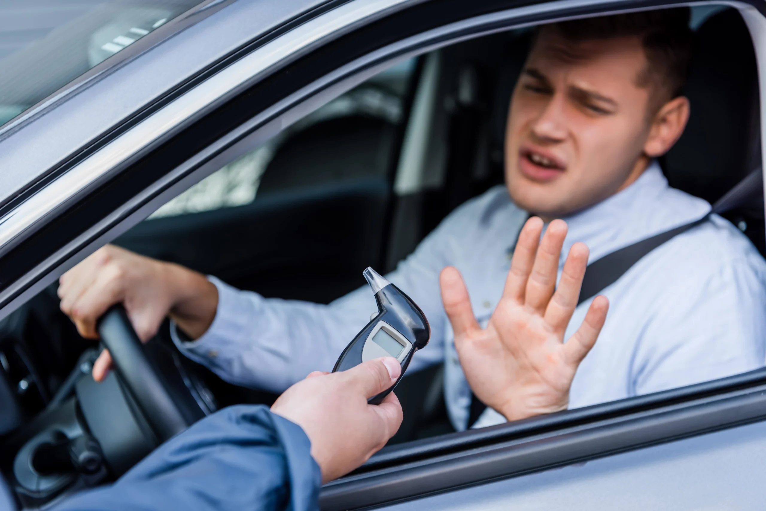 Police holds a breathalyzer to a man in the driver's seat. For aggressive representation for serious DUI charges, contact our dui defense lawyer in Fort Bend County.