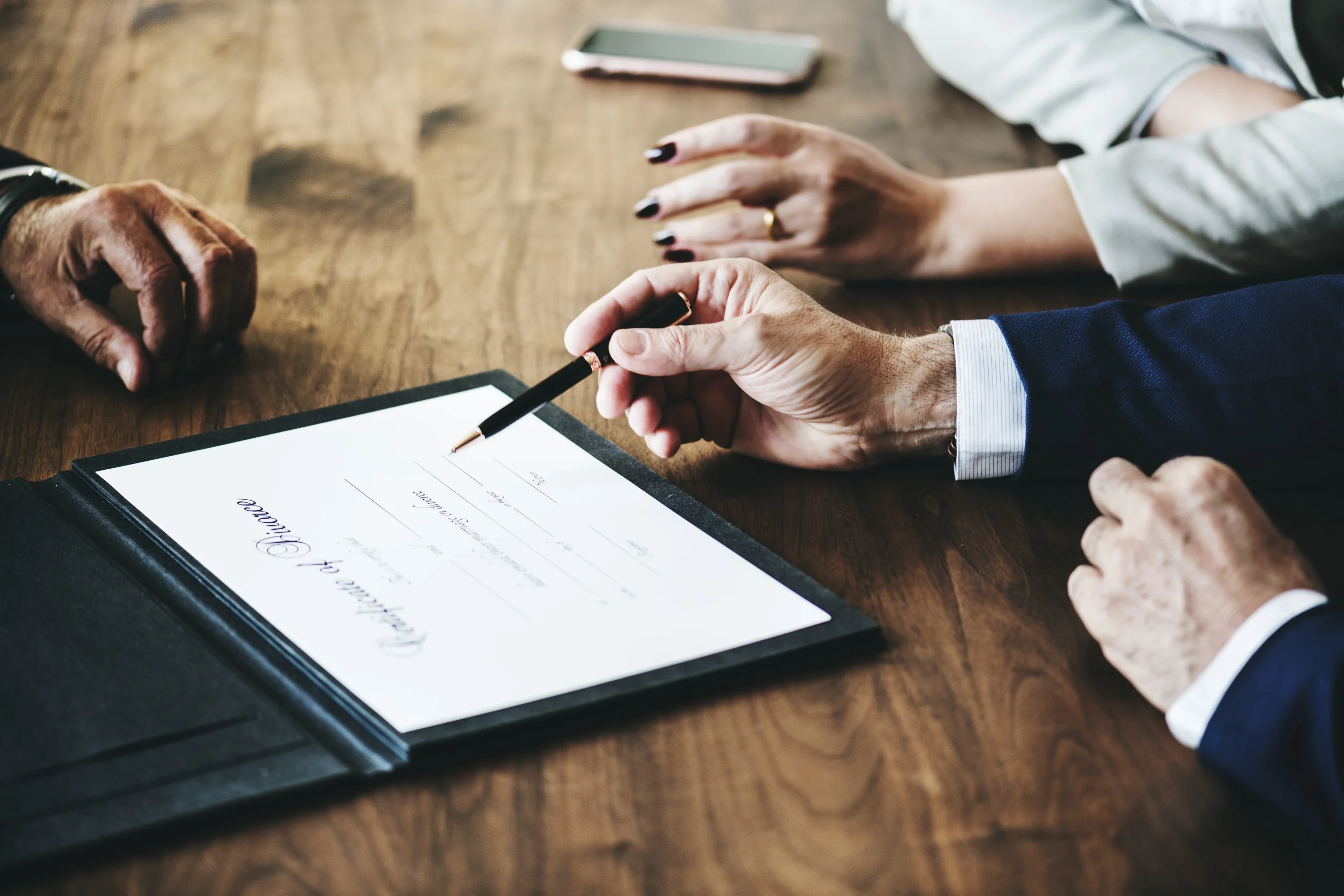 Lawyer holds pen over divorce paper in front of man and woman. For a strong family lawyer in Harris County, contact our experienced legal team today.