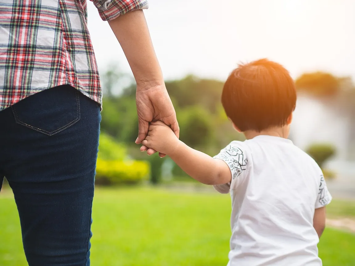 A mom and son walking together outside.