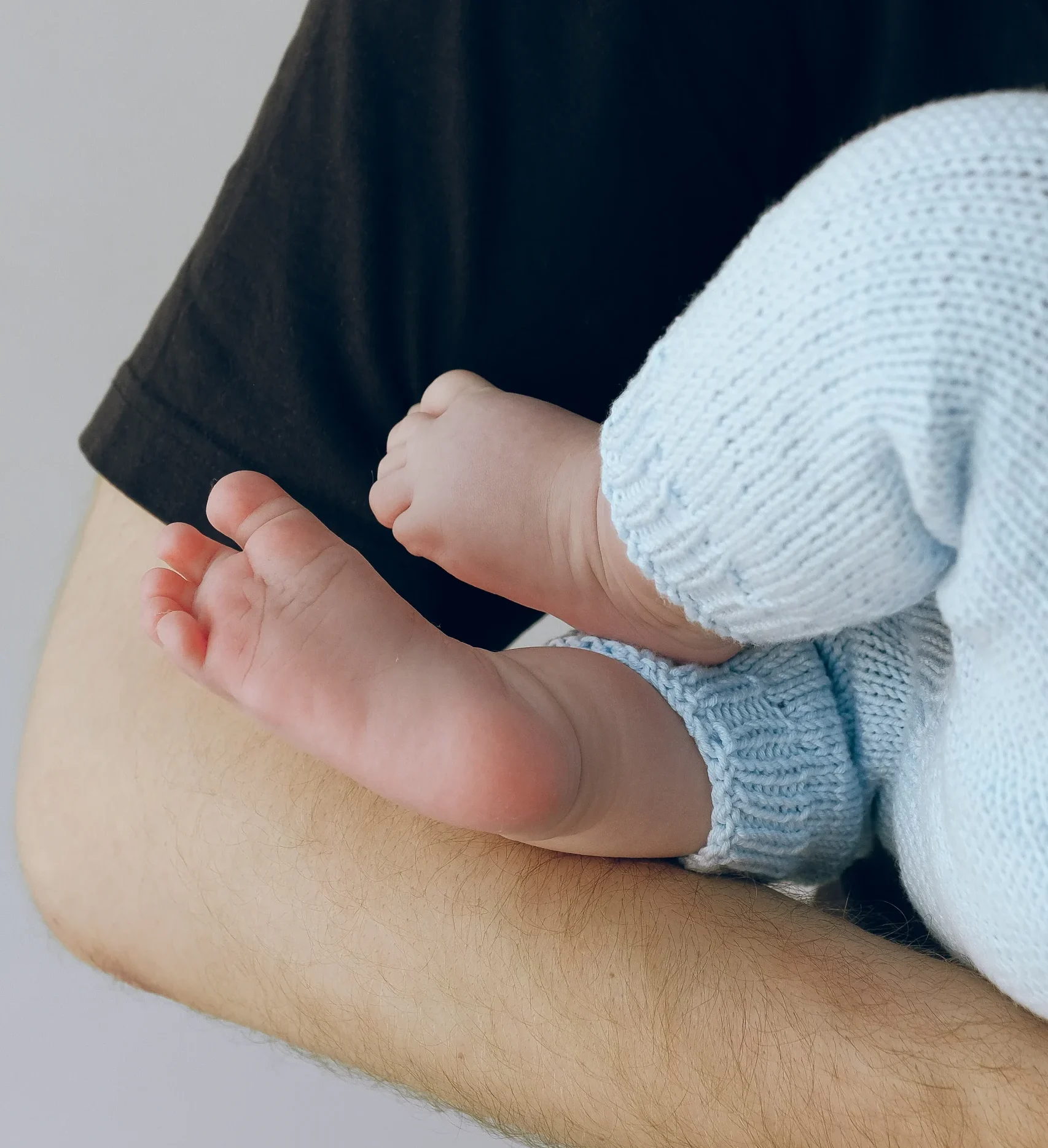Baby being held by their parent. Close up on the feet.