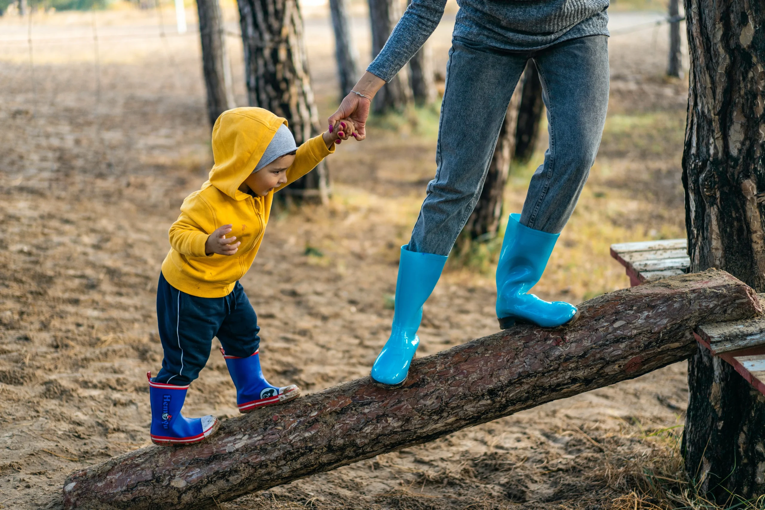 Child being lead on a log by their parent,