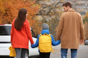 Two parents walking with their child between them, on an urban street.