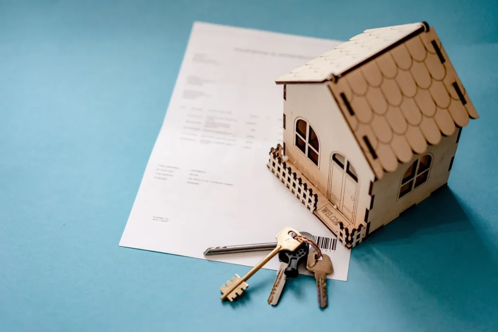 A model house, a keychain with keys sitting on a piece of paper.