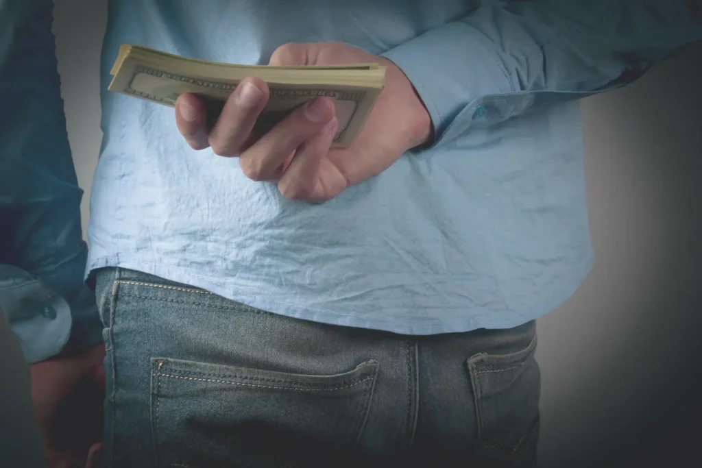 A man hiding money behind his back.