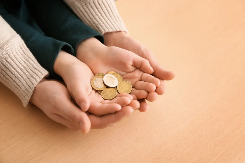 A parent and child holding handful of coins.