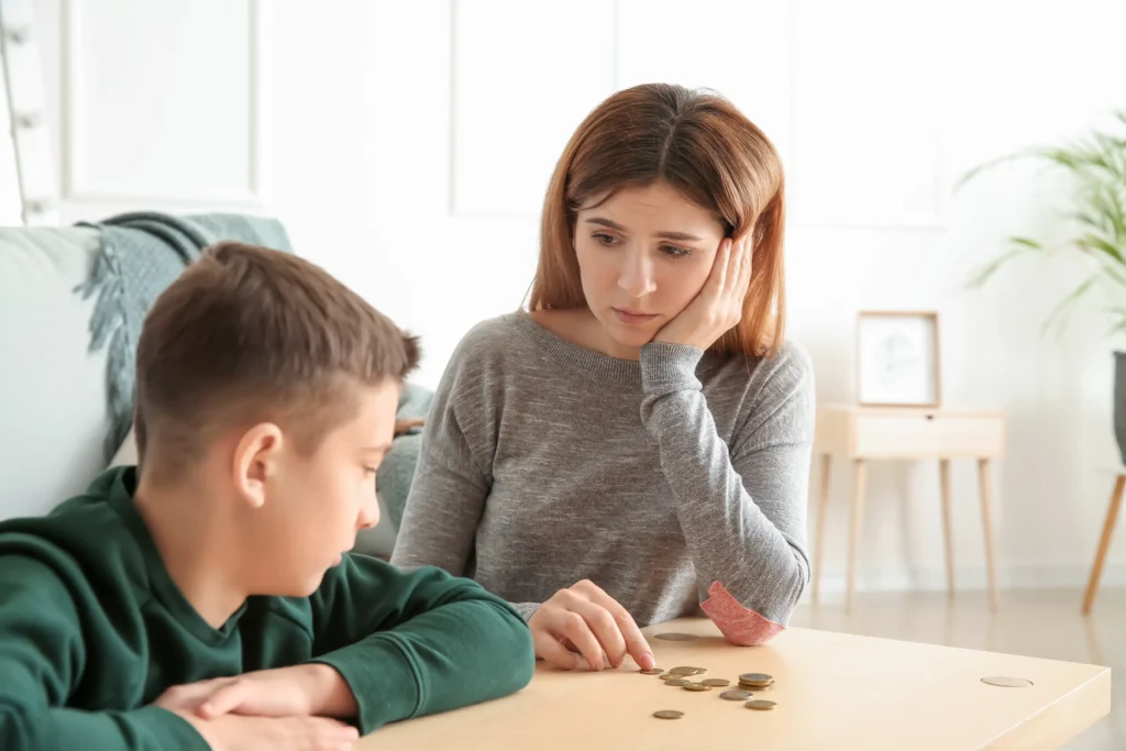 A mother and son counting coins on their table.