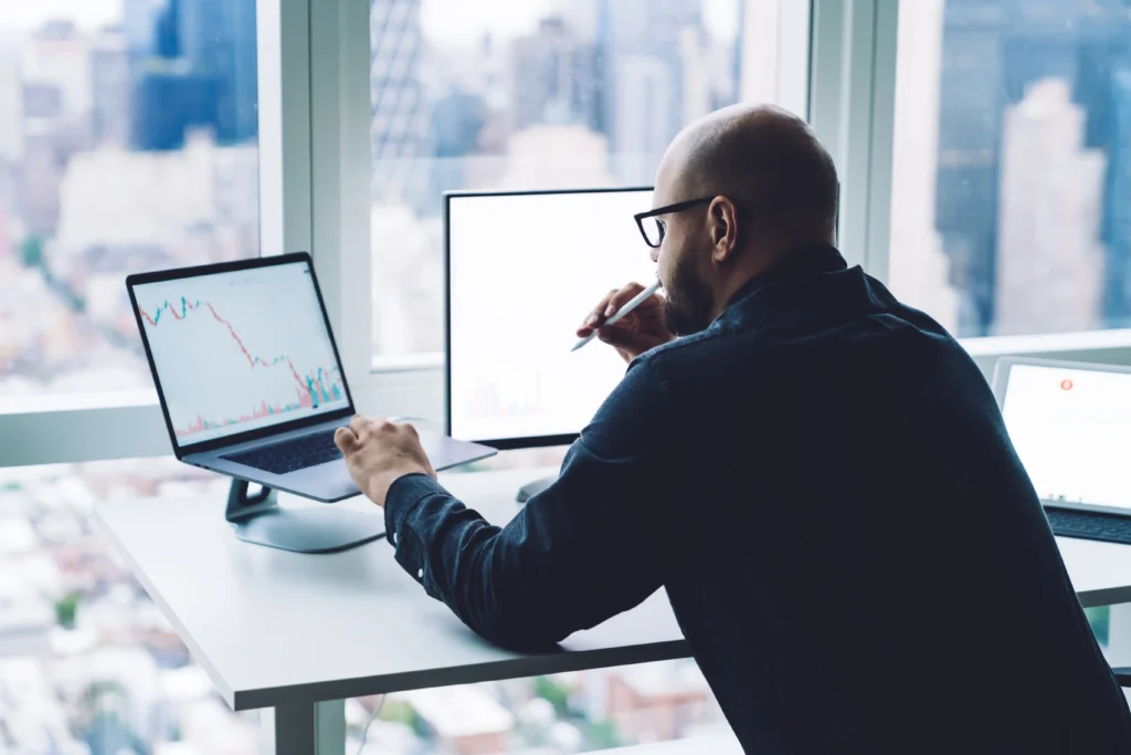 A man looking at charts on his computer.