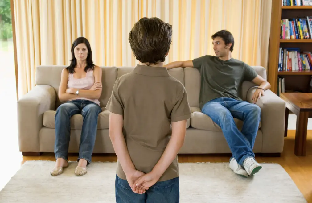 Child in front of their parents as they look distant from each other.